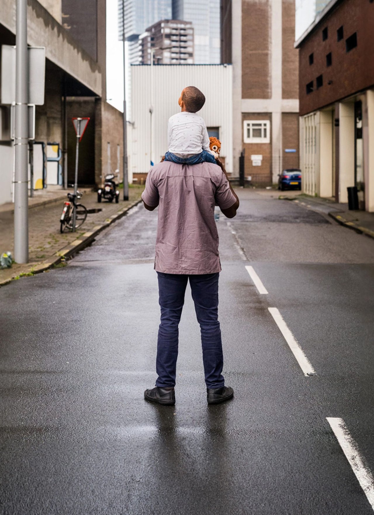 Vader met kind op zijn schouders tussen de gebouwen
